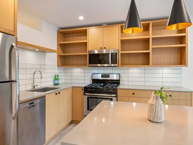 Kitchen featuring appliances with stainless steel finishes, light brown cabinetry, open shelves, and recessed lighting