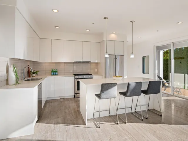 Kitchen featuring modern cabinets, stainless steel appliances, pendant lighting, a kitchen island, and light wood finished floors