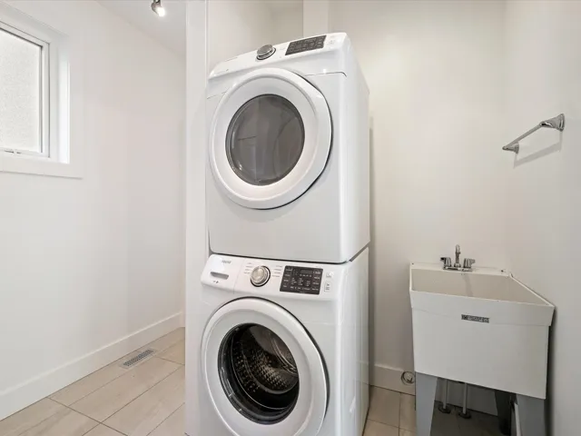 Laundry area featuring estacked washer and dryer and light tile patterned flooring