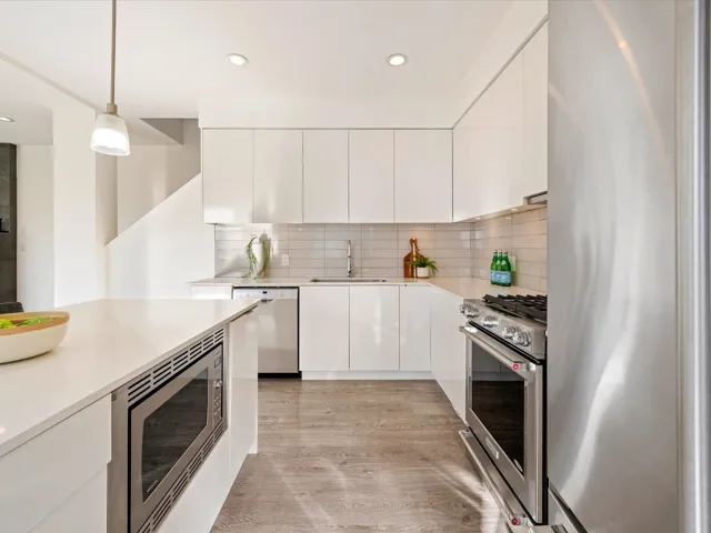 Kitchen with stainless steel appliances, pendant lighting, modern cabinets, white cabinetry, and light wood-type flooring