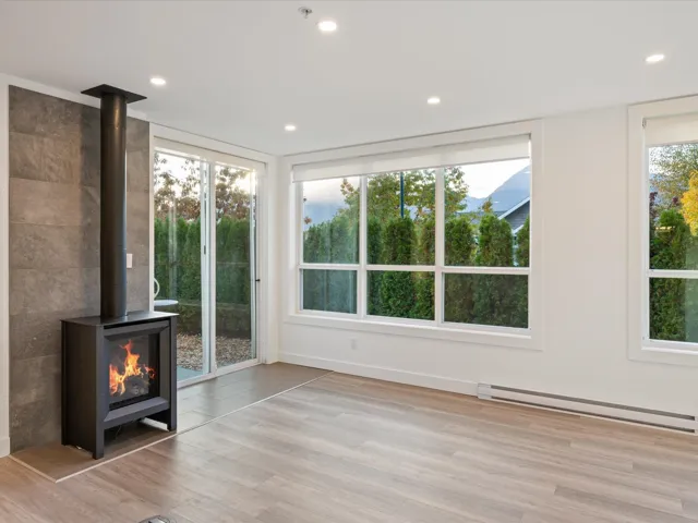 Unfurnished living room featuring a wood stove, a baseboard heating unit, recessed lighting, light wood-type flooring, and healthy amount of natural light
