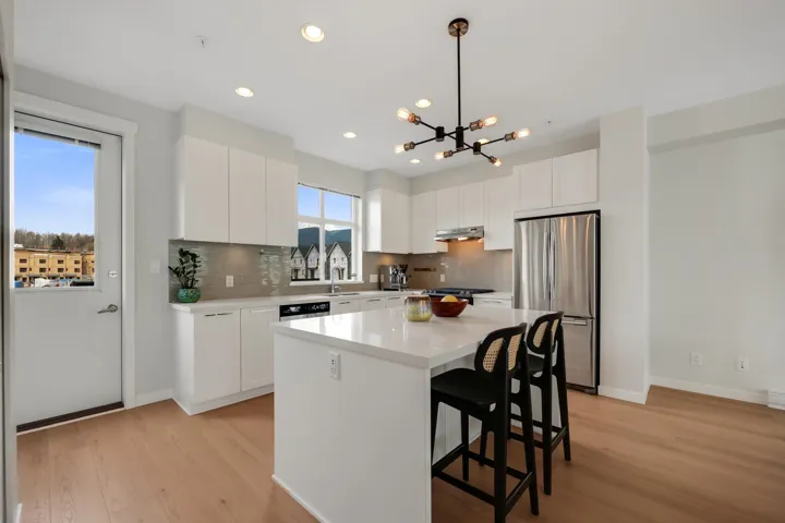 Kitchen with freestanding refrigerator, white cabinets, light wood finished floors, and a kitchen breakfast bar
