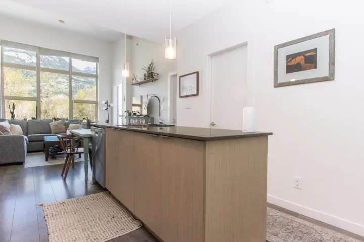 Kitchen featuring dark countertops, stainless steel dishwasher, a sink, modern cabinets, and a center island with sink