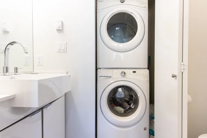 Washroom with stacked washer and clothes dryer and a sink
