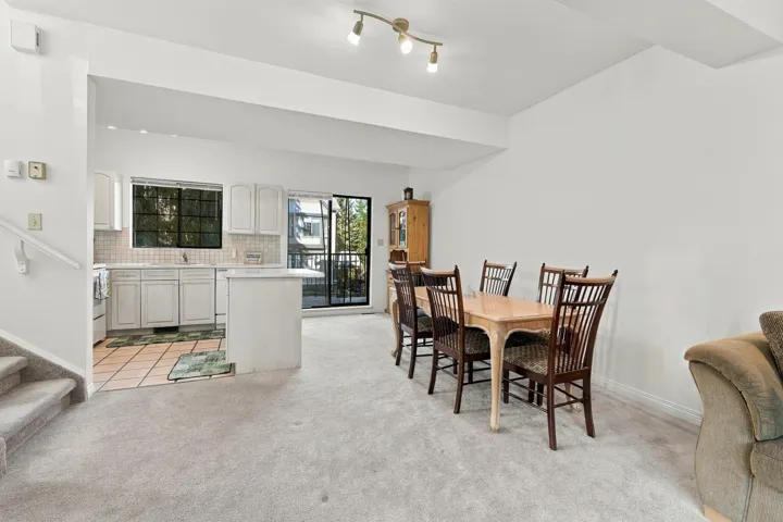 Kitchen area featuring white cabinetry, a center island with counter seating, tile flooring, and a sliding glass door providing external access