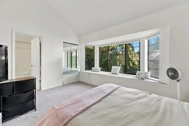 Vaulted ceiling, expansive bay window with integrated bench seating, and mirrored closet doors