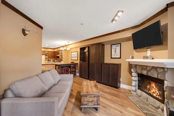 Living area featuring crown molding, light wood-style floors, a fireplace, and a chandelier