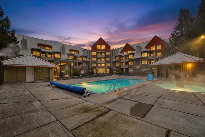 Pool at dusk with a community pool, a gazebo, a hot tub, and a patio area