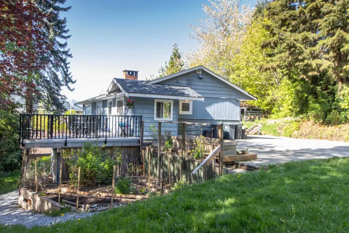 Back of property featuring a shingled roof, a garden, a chimney, and a deck