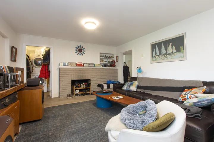 Living room featuring stacked washer and clothes dryer, wood finished floors, and a brick fireplace