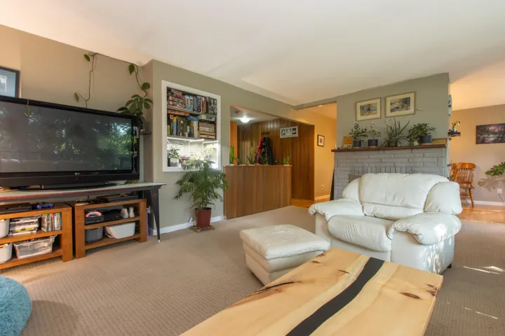 Living area featuring carpet, baseboards, and a brick fireplace