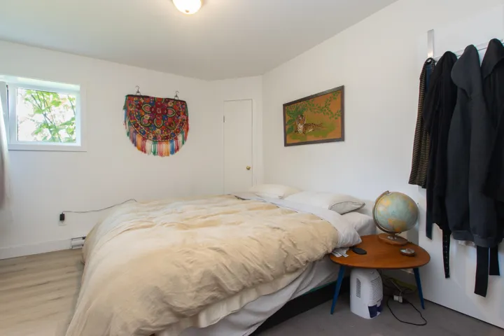 Bedroom with light wood finished floors, baseboards, and a baseboard heating unit