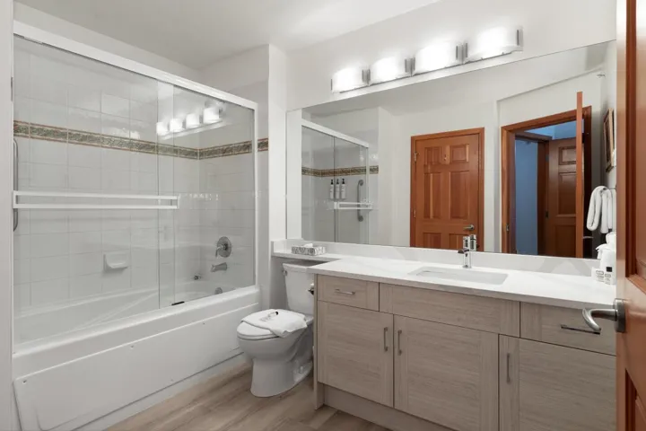 Full bath featuring toilet, enclosed tub / shower combo, vanity, and wood finished floors