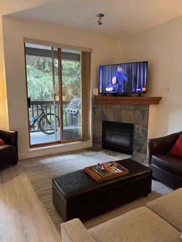 Living room featuring a fireplace with flush hearth and wood finished floors