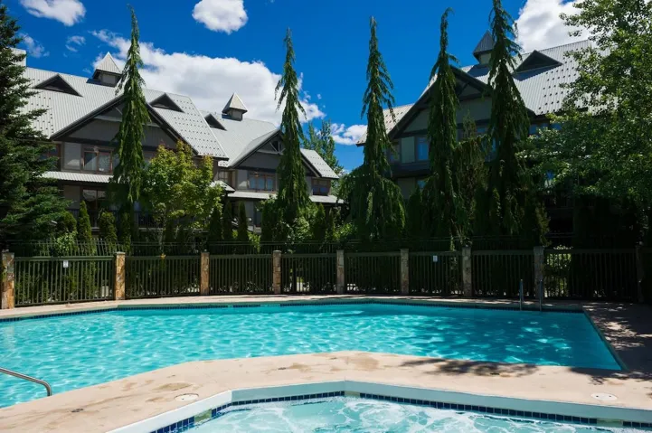 View of pool with fence and a hot tub