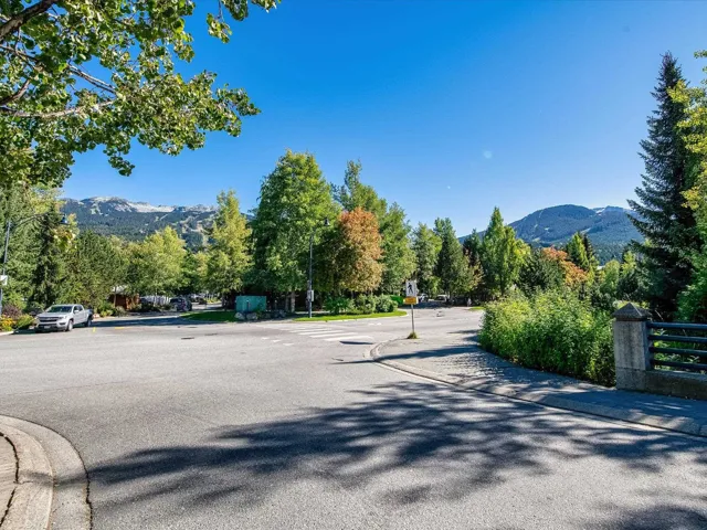 View of asphalt road with a mountain view, curbs, sidewalks, and traffic signs
