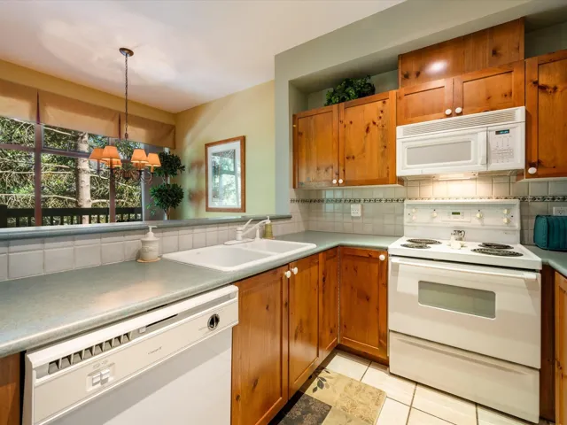 Kitchen featuring white appliances, decorative backsplash, plenty of natural light, and brown cabinets
