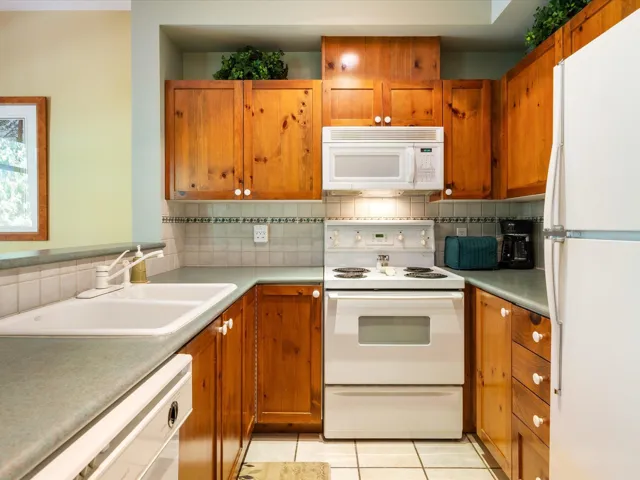 Kitchen with white appliances, decorative backsplash, and brown cabinets