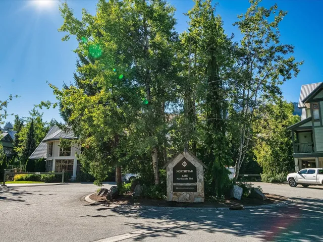 Obstructed view of property featuring stone siding and a metal roof