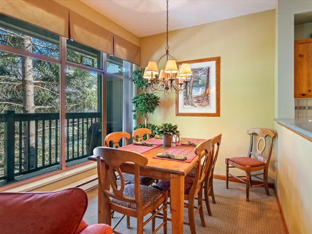 Carpeted dining space with baseboards and a chandelier