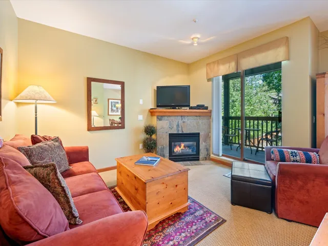 Carpeted living area with a stone fireplace and baseboards