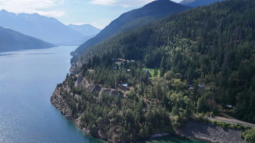 Expansive lake frontage with mountainous terrain and dense tree coverage