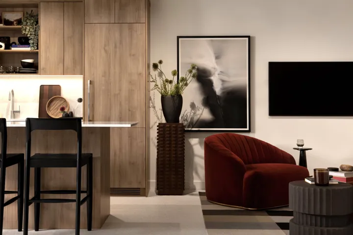 Integrated kitchen and living area featuring custom wood-finish cabinetry, a built-in paneled refrigerator, and a kitchen island with a white countertop