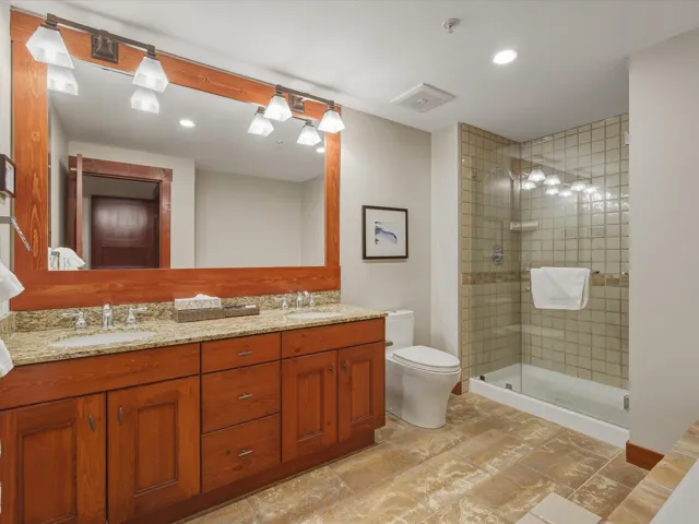 Full bath with double vanity, recessed lighting, and a shower stall