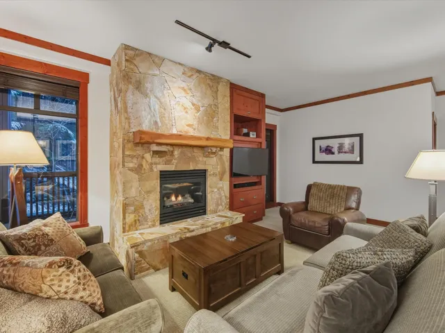 Carpeted living room with a fireplace, track lighting, and ornamental molding