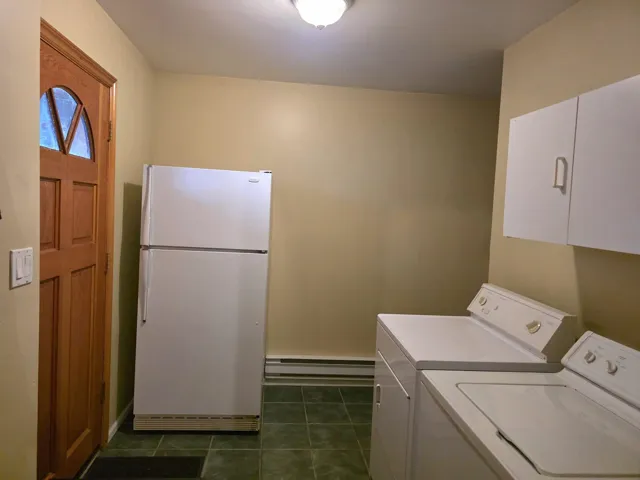 Laundry area featuring a baseboard heating unit, dark tile patterned flooring, and washer and dryer