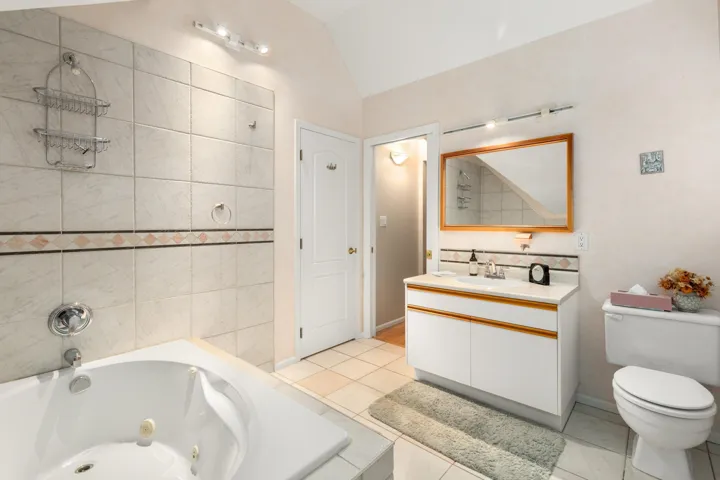 Semi-Primary Bathroom featuring vanity, lofted ceiling, and light tile patterned floors