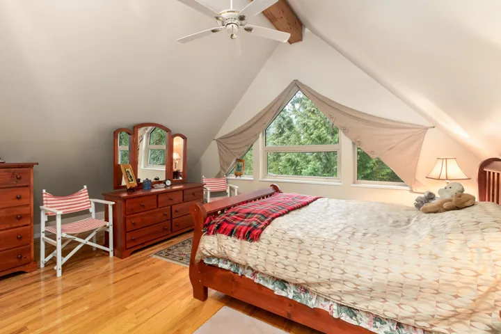 Upper floor Primary Bedroom featuring light wood-type flooring, beam ceiling, and a ceiling fan