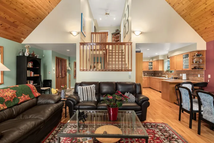 Living area with a vaulted wood ceiling, light wood-style flooring, and a ceiling fan