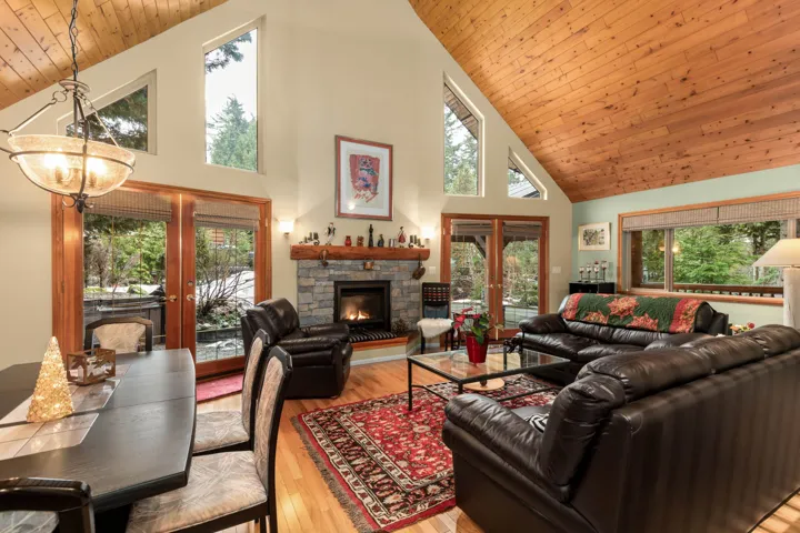 Living area with light wood-style flooring, a stone fireplace, a vaulted wood ceiling, and french doors