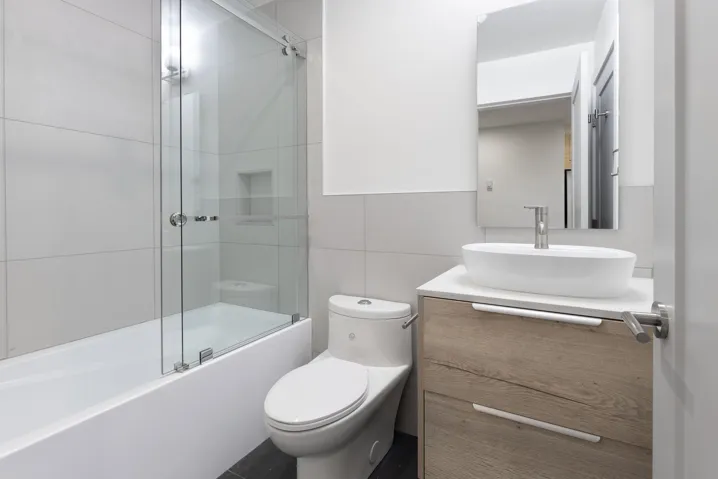 Full bathroom with tile walls, vanity, and combined bath / shower with glass door
