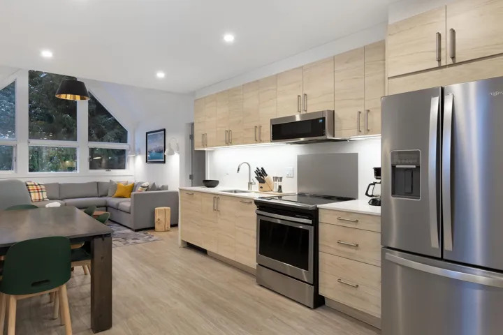 Kitchen with stainless steel appliances, light brown cabinets, open floor plan, lofted ceiling, and modern cabinets