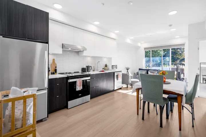 Two tone kitchen with two tone cabinets, stainless steel appliances, modern cabinets, light wood-style floors, and range hood