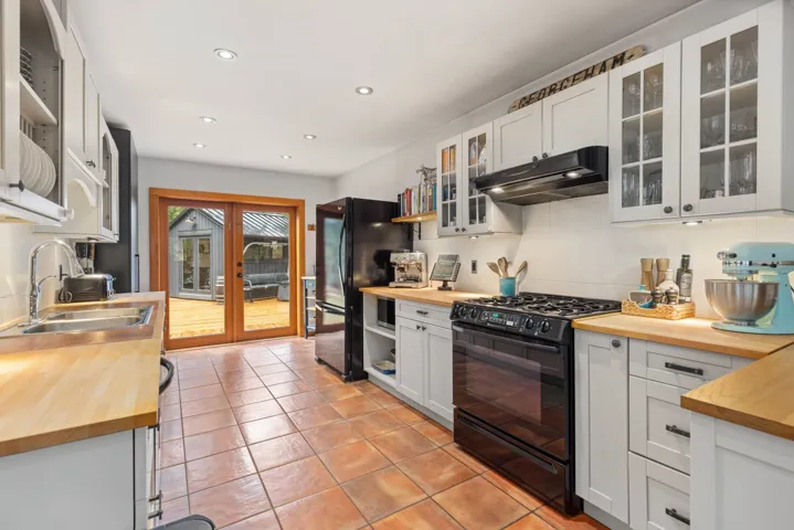 Kitchen with a sink, wood counters, black appliances, and under cabinet range hood