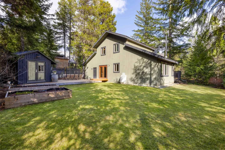 Back of house with an outbuilding, a deck, a storage unit, and a yard