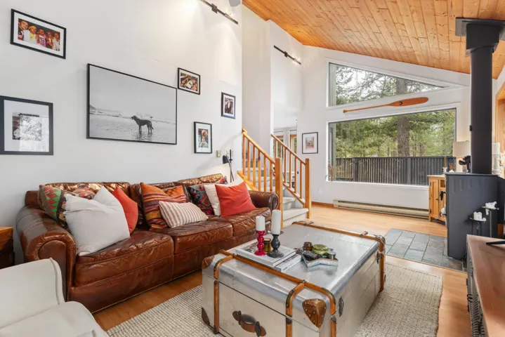 Living area with stairway, a baseboard heating unit, a wood stove, wood ceiling, and wood finished floors