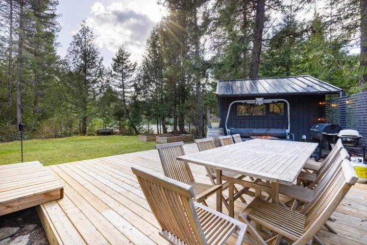 Wooden deck with outdoor dining area, a grill, and a lawn