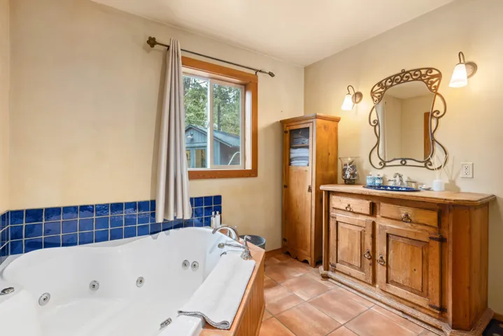 Bathroom with tile patterned floors, vanity, a jetted tub, and baseboards