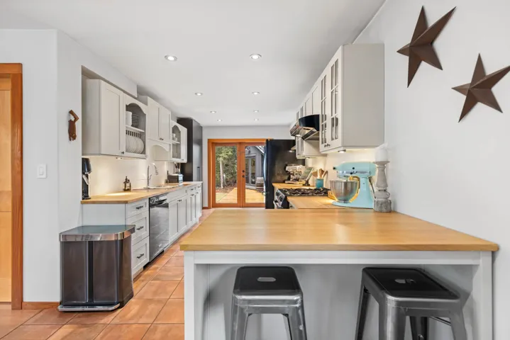 Kitchen with glass insert cabinets, a sink, dishwashing machine, a breakfast bar area, and freestanding refrigerator
