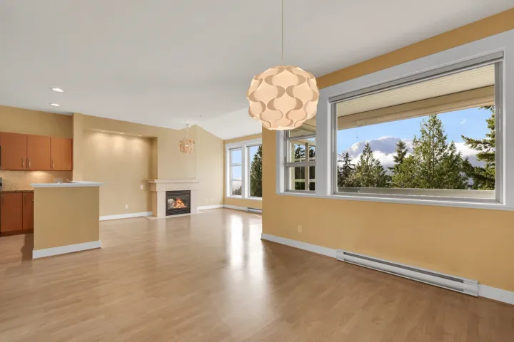 Unfurnished living room with a baseboard heating unit, a fireplace with flush hearth, light wood finished floors, and recessed lighting