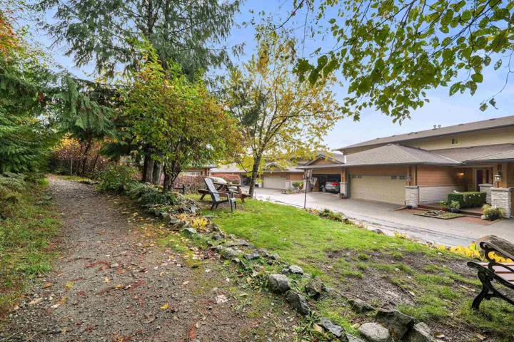 View of green lawn featuring an attached garage and driveway