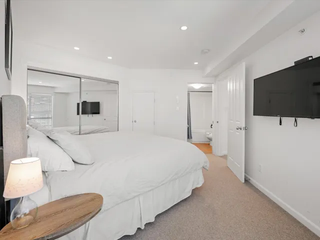 Bedroom featuring a closet, recessed lighting, baseboards, light carpet, and ensuite bath