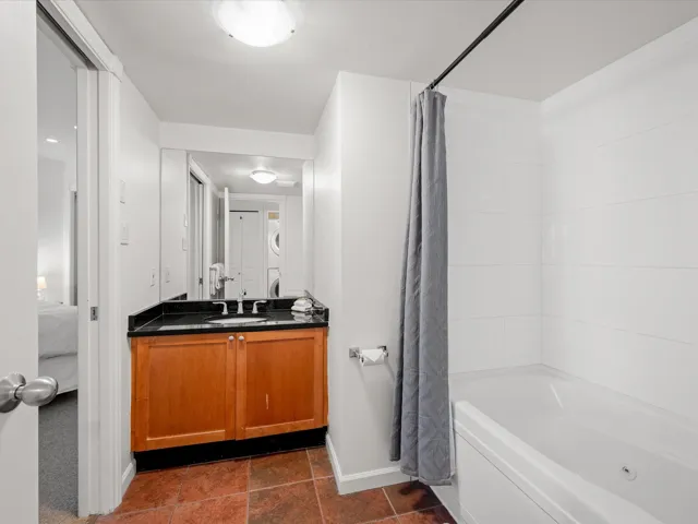 Ensuite bathroom with baseboards, vanity, and shower / bathtub combination with curtain