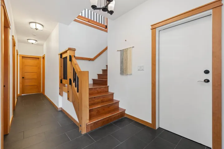 Foyer entrance featuring stairs, dark tile patterned flooring, and baseboards