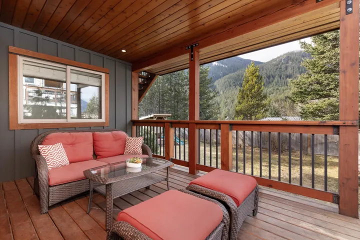 Wooden deck with an outdoor hangout area, a wooded view, and a mountain view