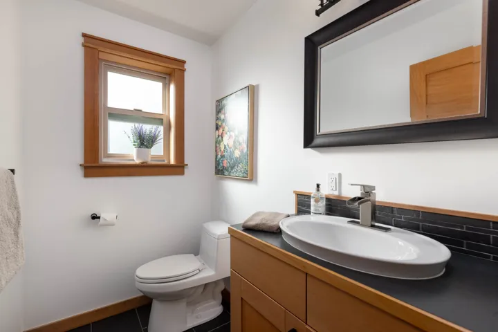 Bathroom featuring decorative backsplash, toilet, vanity, baseboards, and tile patterned floors